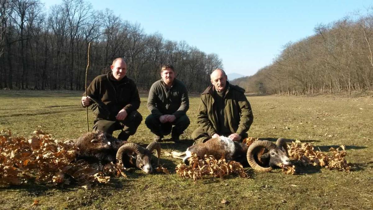 Three hunters kneeling with a small game bag after a hunt in Hungary